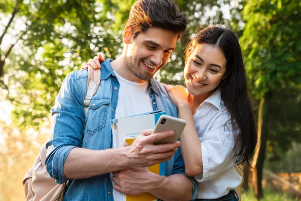 Obrázek Veselého Multikulturního Studentského Páru Mobilním Telefonem Úsměvem Při Procházce — Stock fotografie