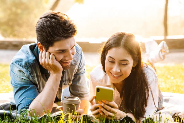 Immagine Gioiosa Coppia Multiculturale Che Usa Cellulare Beve Caffè Asporto — Foto Stock