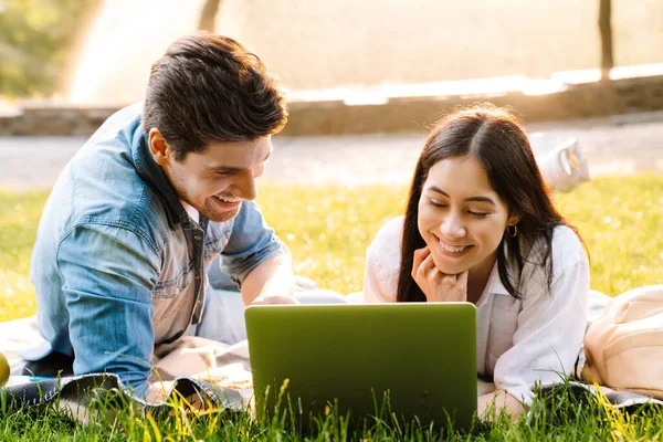 Imagem Casal Multicultural Alegre Usando Laptop Sorrindo Enquanto Estava Deitado — Fotografia de Stock