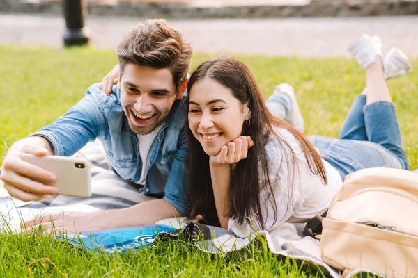 Immagine Felice Coppia Multiculturale Scattare Selfie Smartphone Sorridente Mentre Sdraiato — Foto Stock