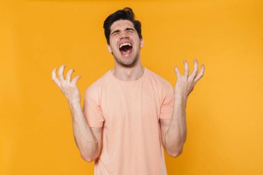 Sarı arka planda elleri kusan mutsuz ve yakışıklı bir adamın fotoğrafı.