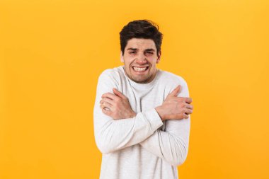 Sıradan giyinmiş hasta bir adamın fotoğrafı. Kameraya bakıyor ve sarı arka planda kendini soyutluyor.