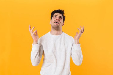 Hasta, mutsuz, sıradan giyinmiş bir adamın fotoğrafı yukarı bakıyor ve sarı arka planda yalnız başına ağlıyor.