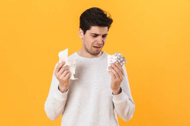 Alerjisi olan, haplı ve sarı arka planda izole edilmiş peçeteli mutsuz adamın fotoğrafı.