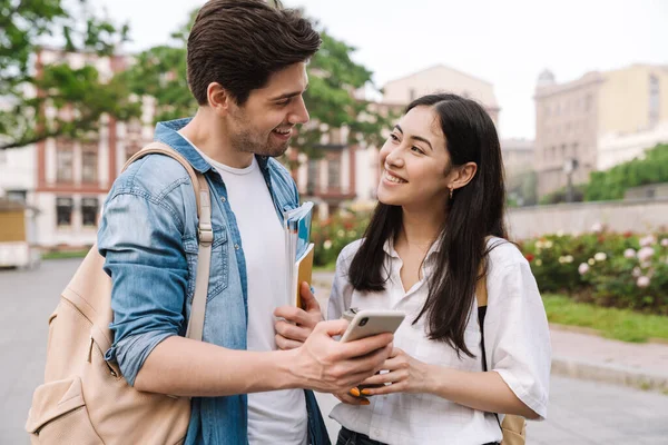 Obraz Radosnej Wielokulturowej Pary Studentów Rozmawiających Korzystających Telefonu Komórkowego Podczas — Zdjęcie stockowe