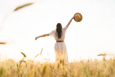 Buğday tarlasında hasır şapkalı, tatlı esmer kadının fotoğrafı.