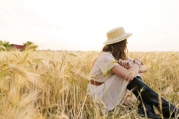 藁帽子の魅力的な白人女性の写真同じ日に小麦畑に座っている間に休んで — ストック写真