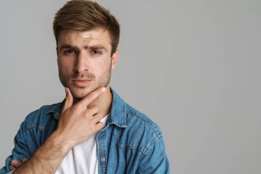 Gri arka planda izole edilmiş, kendine güvenen, poz veren ve kameraya bakan vahşi adamın portresi.
