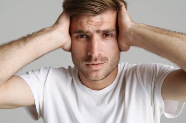 Kızıl saçlı, erkeksi bir adamın portresi. Gri arkaplanda kafasını tutarken kameraya bakıyor.