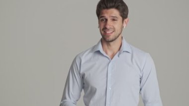 Çekici bir delikanlının yakın plan görüntüsü, beyaz arka planda izole bir şekilde duran kablosuz kulaklıklarını kullanarak telefonda konuşuyor.