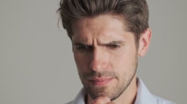 Yakışıklı, tıraşsız bir delikanlının yakın plan görüntüsü beyaz arka planda izole bir şekilde duran iyi bir çözümle ortaya çıkıyor.