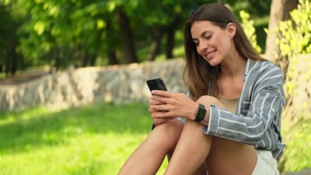 Spokojen Atraktivní Brunetka Žena Pomocí Smartphone Zatímco Sedí Parku — Stock video