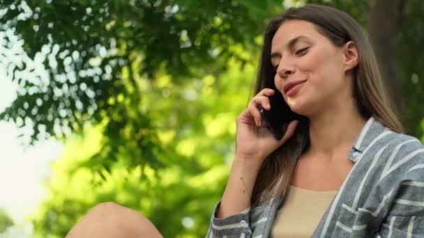 Šťastná Atraktivní Brunetka Žena Mluví Chytrým Telefonem Zatímco Sedí Parku — Stock video