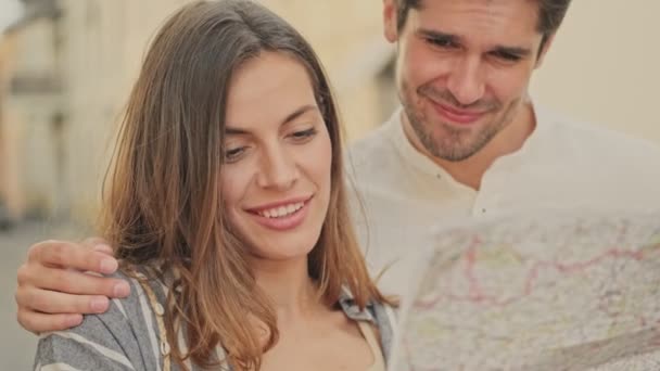 心满意足的年轻漂亮的夫妇站在街上学习城市地图 — 图库视频影像