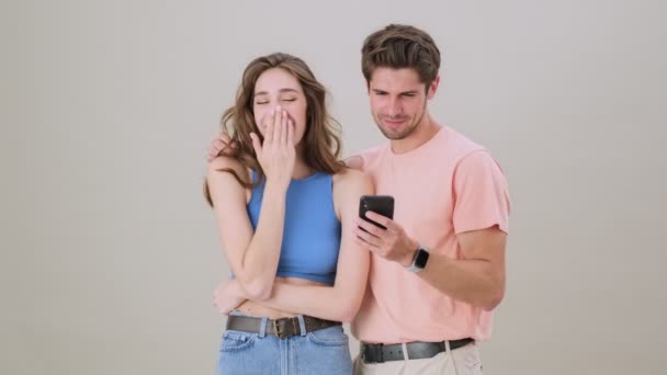 Jovem Casal Encantador Está Lendo Algo Smartphone Rindo Isolado Sobre — Vídeo de Stock