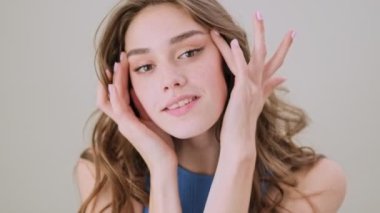 Gri arka planda, stüdyoda, güzel bir genç kadın poz veriyor.