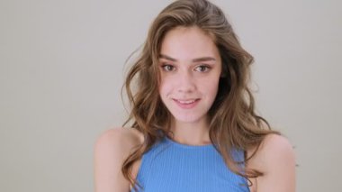 Baştan çıkarıcı genç bir kadın stüdyoda gri arka planda tek başına poz veriyor.