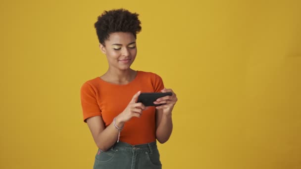 Surprised Attractive African Woman Playing Smartphone Showing Thumb Yellow Background — Stock Video