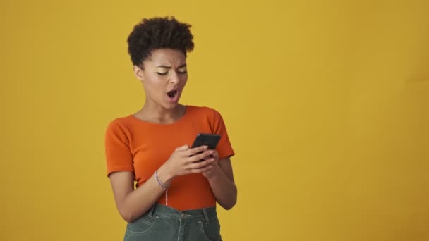 Gelukkig Aantrekkelijke Afrikaanse Vrouw Schrijven Bericht Smartphone Gele Achtergrond — Stockvideo