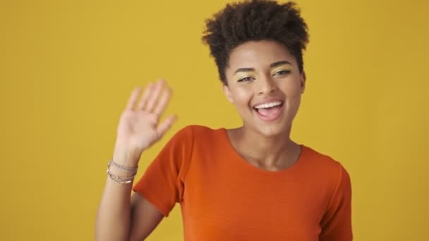 Ευτυχισμένη Ελκυστική Αφρικανή Χαιρετάει Την Κάμερα Πάνω Από Κίτρινο Φόντο — Αρχείο Βίντεο