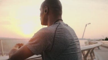 Kulaklıklı genç bir Afrikalı köprüde dikiliyor.