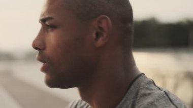 Yakışıklı, genç bir Afrikalı adamın yakından görüntüsü sabah köprüde koştuktan sonra uzaklığa bakıyor.