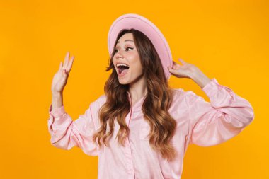 Çekici, heyecanlı, el sallayan ve sarı arka planda izole edilmiş bir kadın görüntüsü.