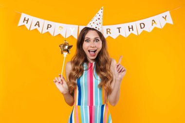 Heyecanlı, sevimli bir kadının yukarı doğru işaret ettiği ve sarı arka planda sihirli değneği tuttuğu görüntü.