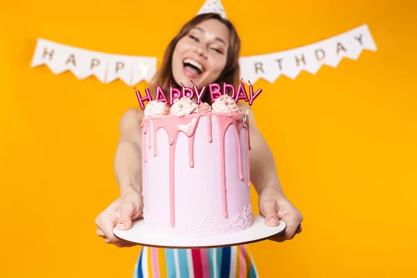 Bild Der Aufgeregten Jungen Frau Partykegel Zeigt Geburtstagstorte Und Lächelt — Stockfoto