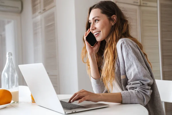 Hübsche Fröhliche Junge Frau Frühstückt Während Sie Küchentisch Sitzt Laptop — Stockfoto