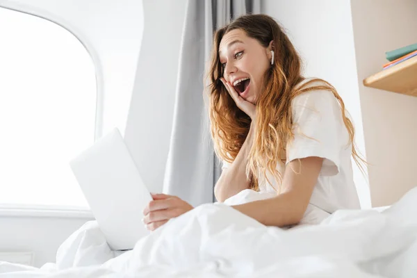 Portrett Opphisset Kvinne Med Øretelefon Som Uttrykker Overraskelse Smil Mens – stockfoto