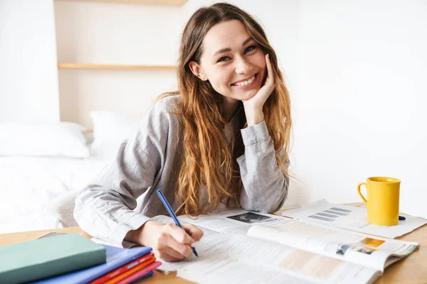 Foto Von Lächelnden Schönen Studentin Schreiben Auf Schulheft Während Hausaufgaben — Stockfoto