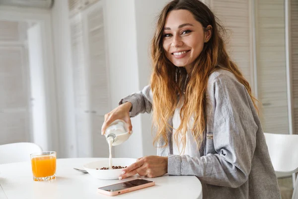 照片上 美丽的高加索女人在白色厨房吃早餐时面带微笑 — 图库照片