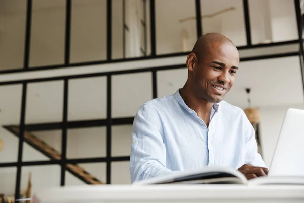 Foto Homem Afro Americano Sorridente Trabalhando Com Laptop Enquanto Senta — Fotografia de Stock