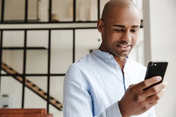 Photo Smiling African American Man Using Mobile Phone While Working — Stock Photo, Image