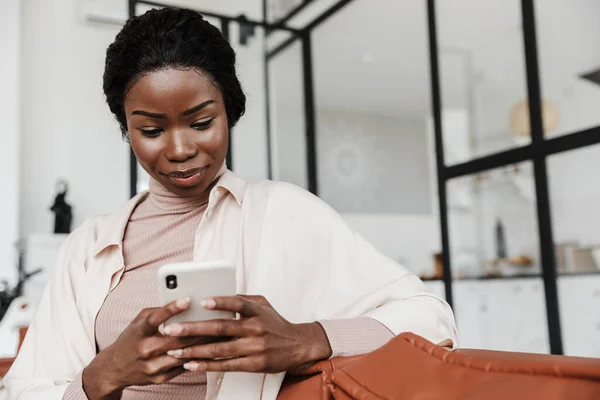 Imagen Increíble Mujer Africana Concentrada Sentada Sofá Casa Mientras Usa — Foto de Stock