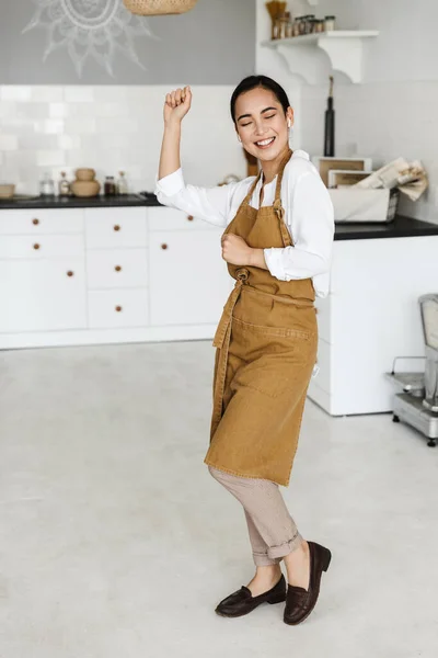 Vrolijke Jonge Aziatische Vrouw Dragen Schort Dansen Tijdens Het Luisteren — Stockfoto