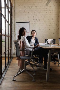 Modern bir ofiste yeni bir proje üzerinde çalışan iki çekici, gülümseyen, çok ırklı, zeki kadın girişimci.