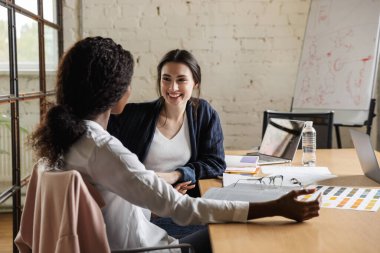 Modern bir ofiste yeni bir proje üzerinde çalışan iki çekici, gülümseyen, çok ırklı, zeki kadın girişimci.