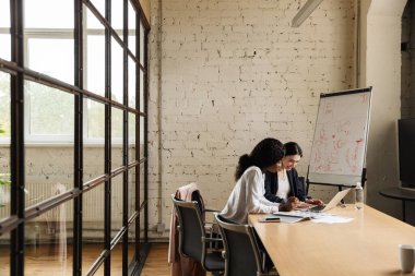 Kendine güvenen akıllı kadın girişimciler ofis masasında otururken yeni bir proje üzerinde çalışıyorlar.