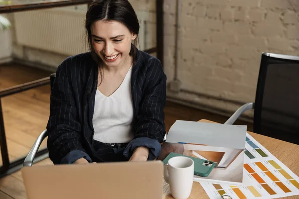 坐在写字台前 自信地微笑着 迷人的年轻女企业家在笔记本电脑上工作 — 图库照片