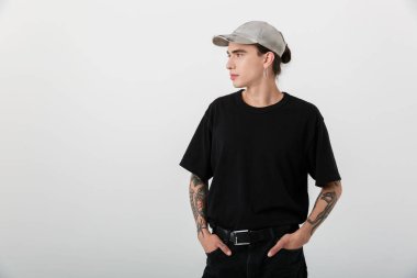 Siyah elbiseli esmer bir gencin portresi. Beyaz arka planda elleri ceplerinde kameraya poz veriyor.