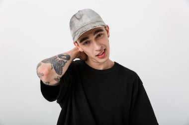 Beyaz arka plan üzerinden kameraya bakan, siyah giyinmiş, kafası karışık, beyaz bir adamın portresi.