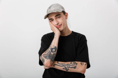 Kafası karışmış siyah elbiseli bir adamın portresi kameraya bakıyor ve kafasını beyaz arka planda destekliyor.