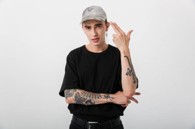 Siyah elbiseli küstah bir gencin portresi kameraya bakıyor ve kendini beyaz arka planda gösteriyor.