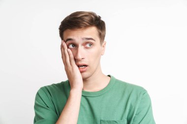 Kafası karışmış, beyaz tişörtlü, stresli beyaz bir adamın beyaz arka plan üzerinden yüzünü kavraması.