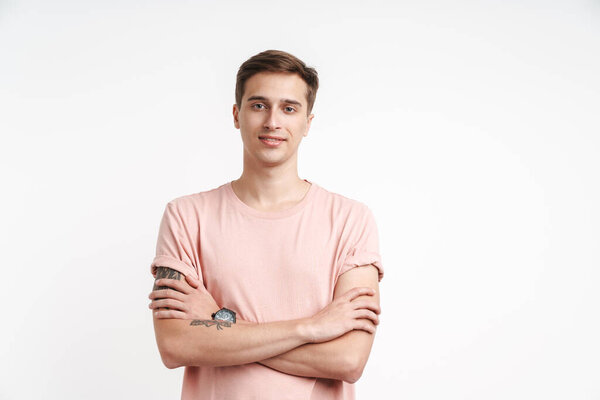Image of attractive caucasian man in basic t-shirt smiling and standing with arms crossed isolated over white background