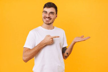 Gözlüklü gülümseyen genç adamın fotoğrafı ve sarı arka planda izole edilmiş telif alanını gösteren bir işaret.