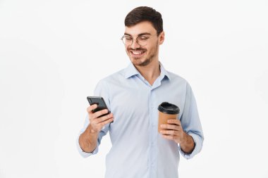 Gözlüklü, kahve içen ve beyaz arka planda izole edilmiş cep telefonu kullanan mutlu beyaz adamın fotoğrafı.