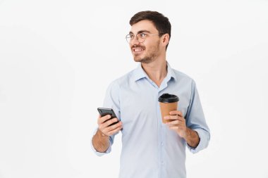 Gözlüklü, kahve içen ve beyaz arka planda izole edilmiş cep telefonu kullanan mutlu beyaz adamın fotoğrafı.